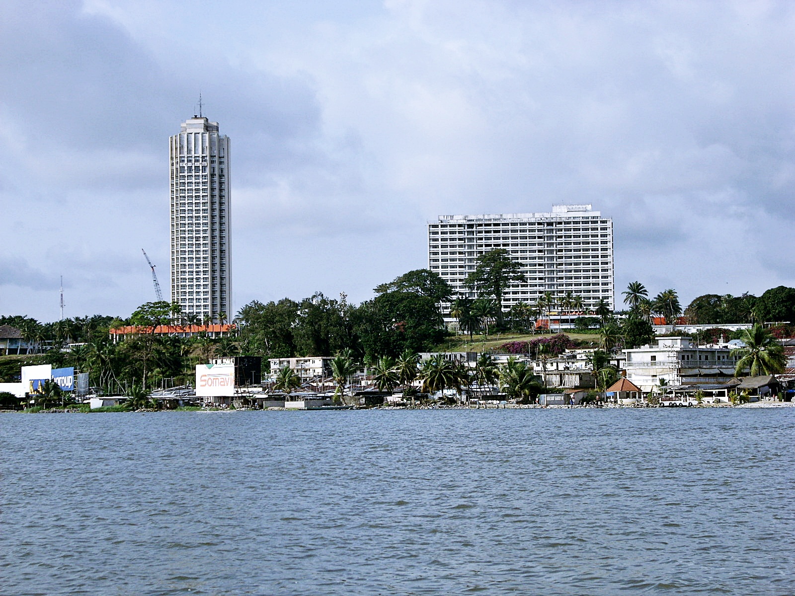La tour de l'hôtel Ivoire dominant la lagune Ébrié à Cocody, Abidjan, sous un ciel nuageux