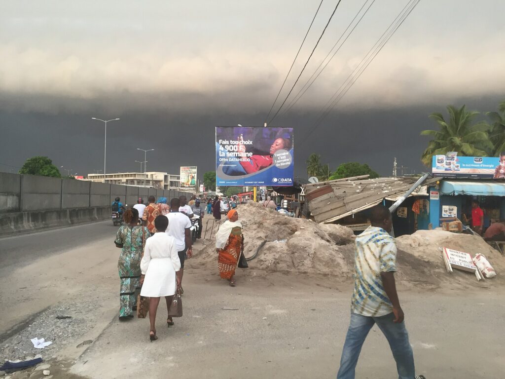 Ciel sombre et menaçant au-dessus d’une rue d’Abidjan en fin de journée, avant un orage