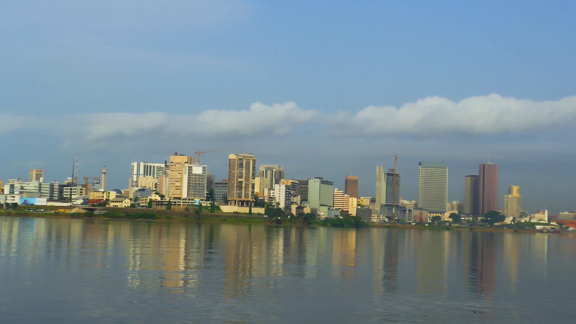 Les tours du Plateau se reflétant dans la lagune Ébrié sous un ciel bleu, à Abidjan