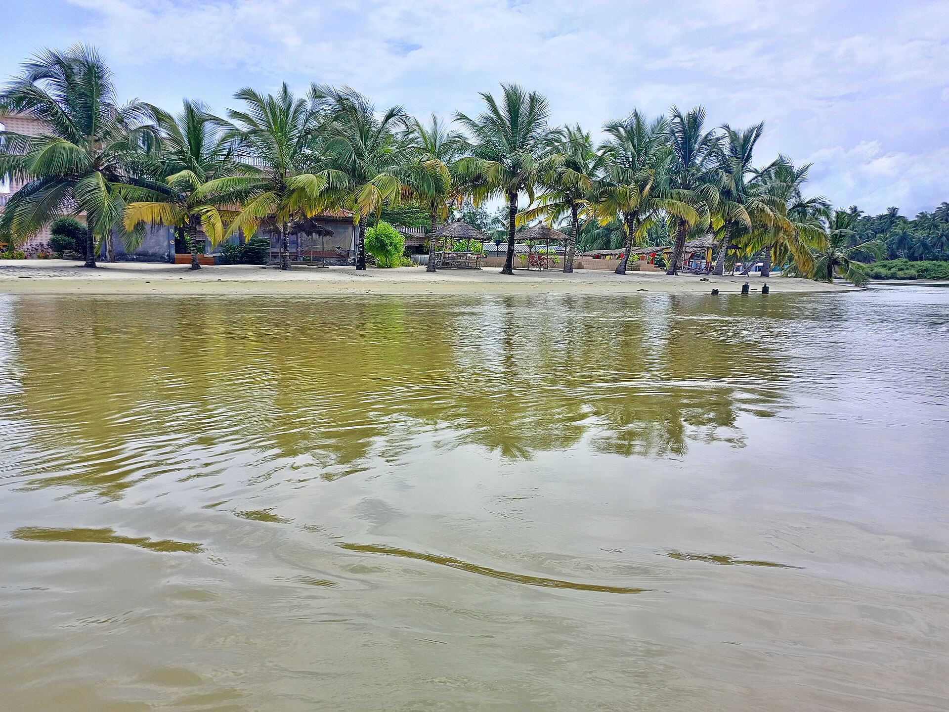 Rive de la lagune bordée de cocotiers et de paillotes à Assinie