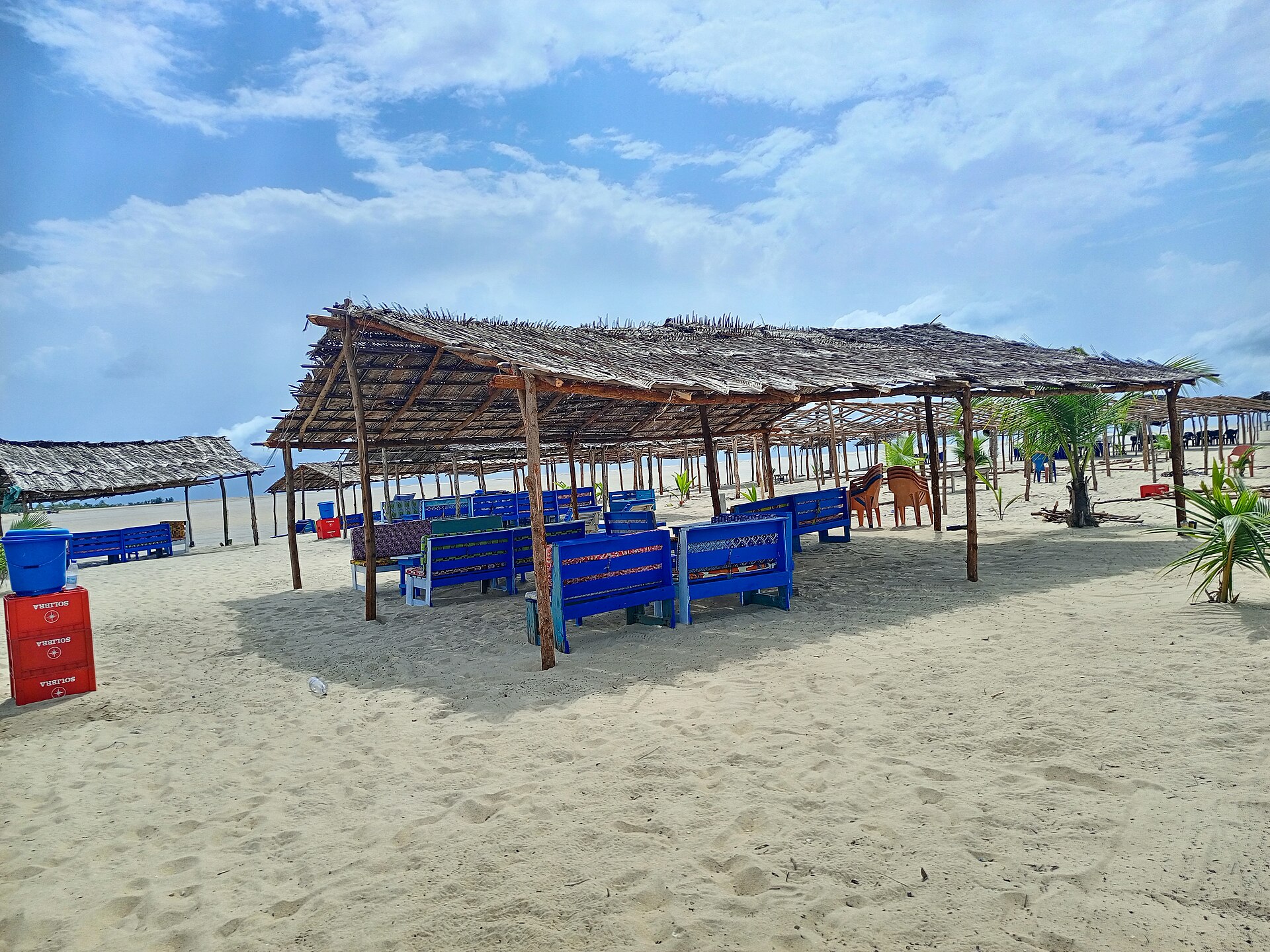 Paillotes et bancs bleus sur la plage de sable blanc d'Assinie