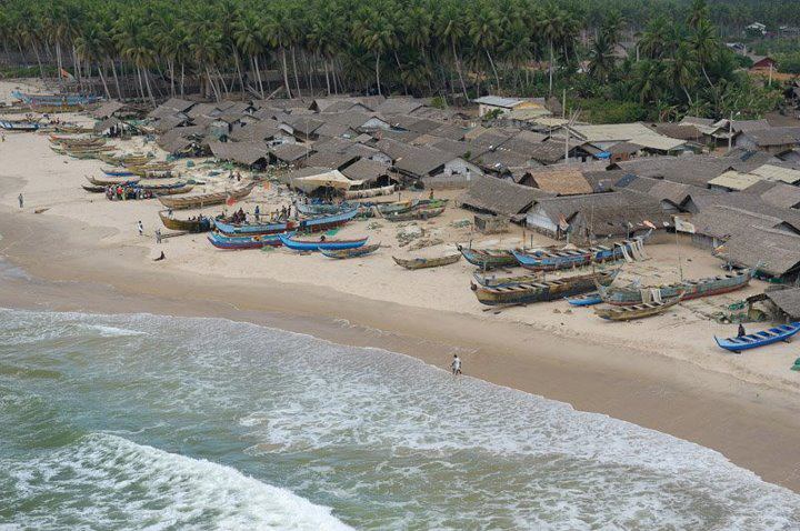 Vue d’un village de pêcheurs à Assinie, pirogues colorées alignées sur la plage entre les cocotiers et l’océan