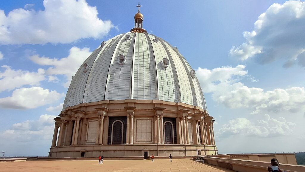Grand dôme blanc et colonnade de la basilique Notre-Dame-de-la-Paix de Yamoussoukro sous un ciel bleu