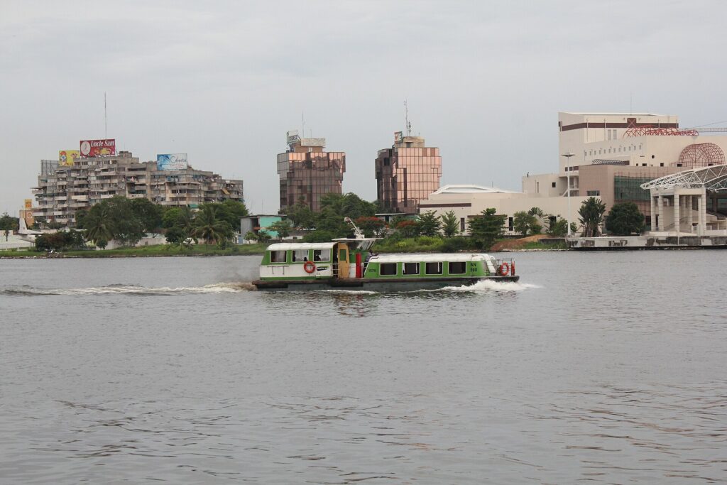 Bateau-bus naviguant sur la lagune Ébrié devant les immeubles d'Abidjan