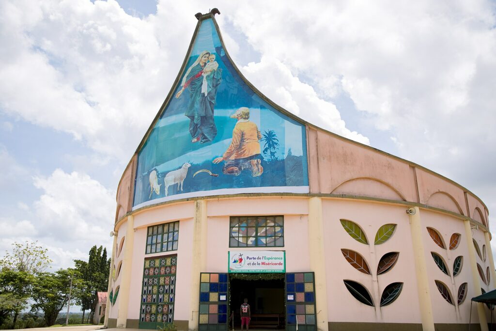 Façade arrondie et colorée du sanctuaire Notre-Dame-de-la-Garde de Bonoua, ornée d’une grande fresque