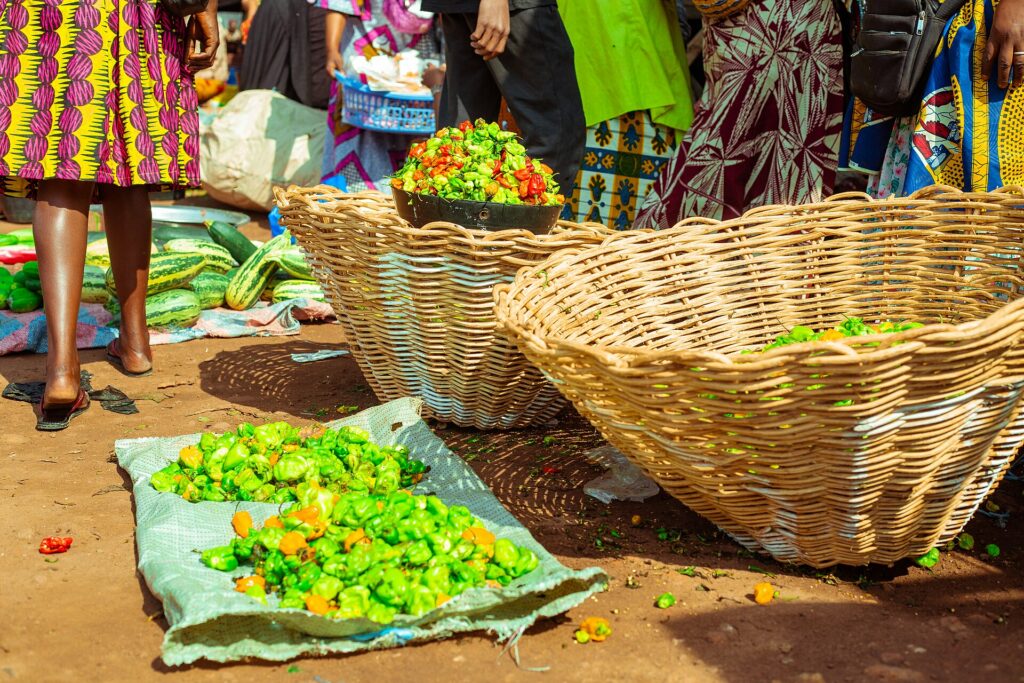 Piments rouges, jaunes et verts disposés en tas sur un étal de marché à Bouaké