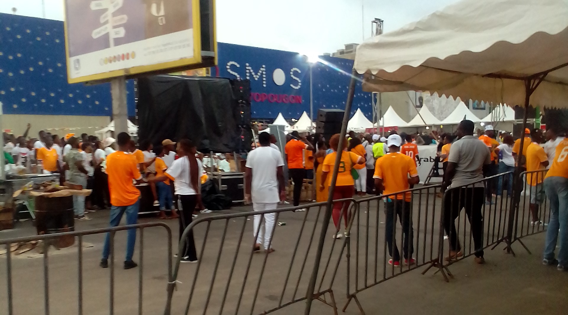 Supporters en maillots orange devant l'entrée de la fan zone de Yopougon pendant la CAN 2023