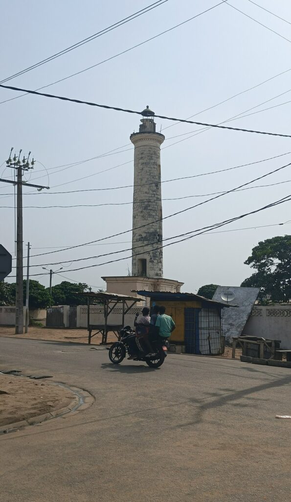Le phare de Grand-Bassam, tour blanche dominant une rue du quartier France