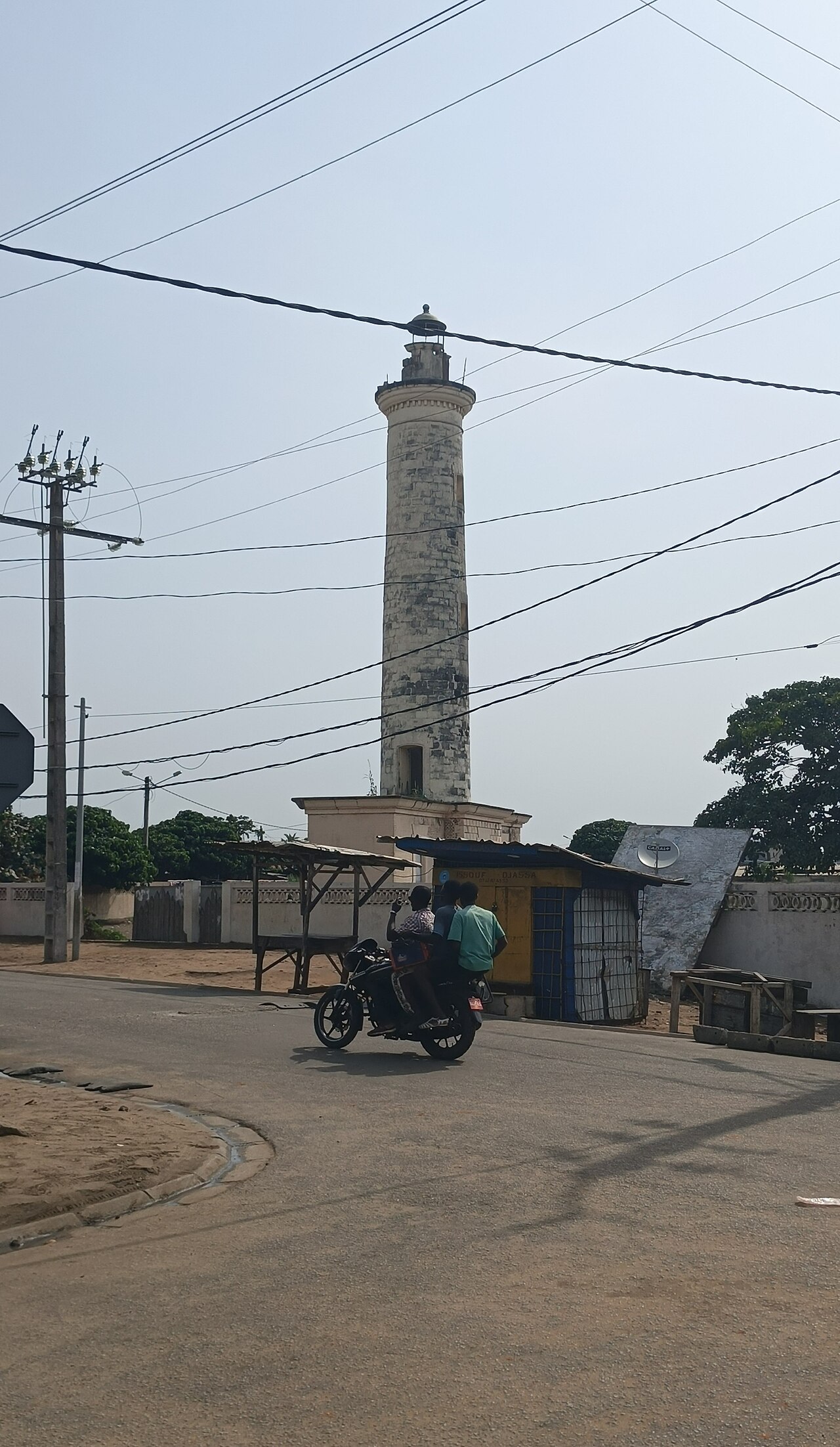 Le phare de Grand-Bassam, tour blanche dominant une rue du quartier France