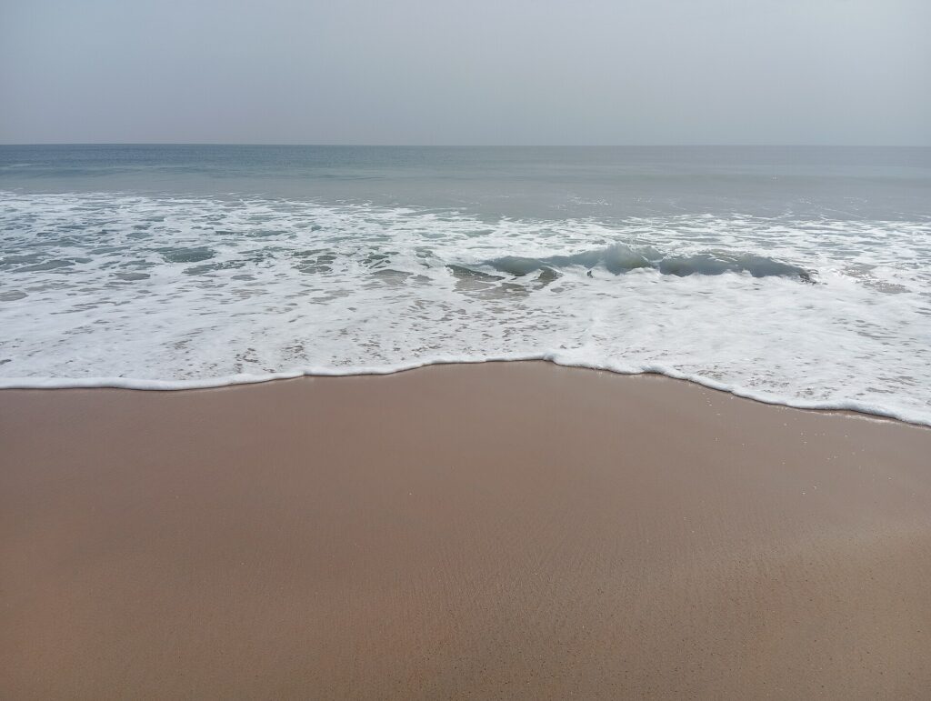 Large plage de sable de Grand-Bassam avec les vagues de l’océan Atlantique