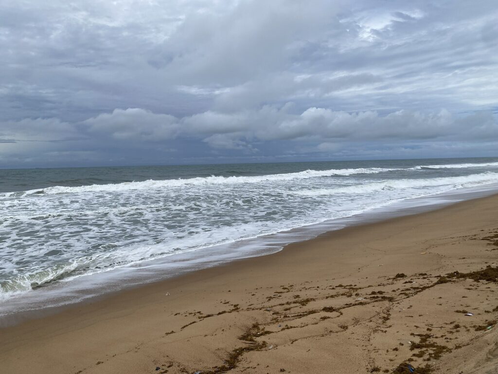 Longue plage de sable de Jacqueville bordée de vagues sous un ciel nuageux