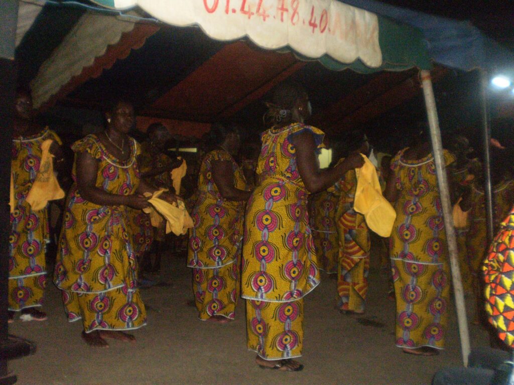 Femmes en pagnes jaunes et rouges exécutant une danse traditionnelle agni sanwi à Krindjabo