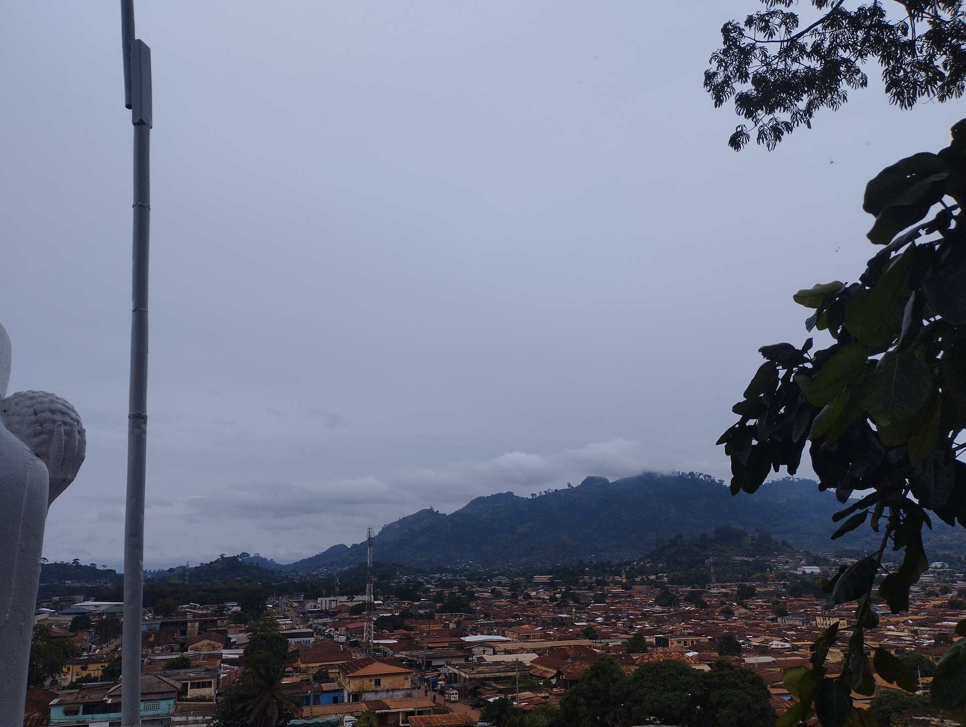 Toits de tôle de la ville de Man et montagnes sous un ciel nuageux
