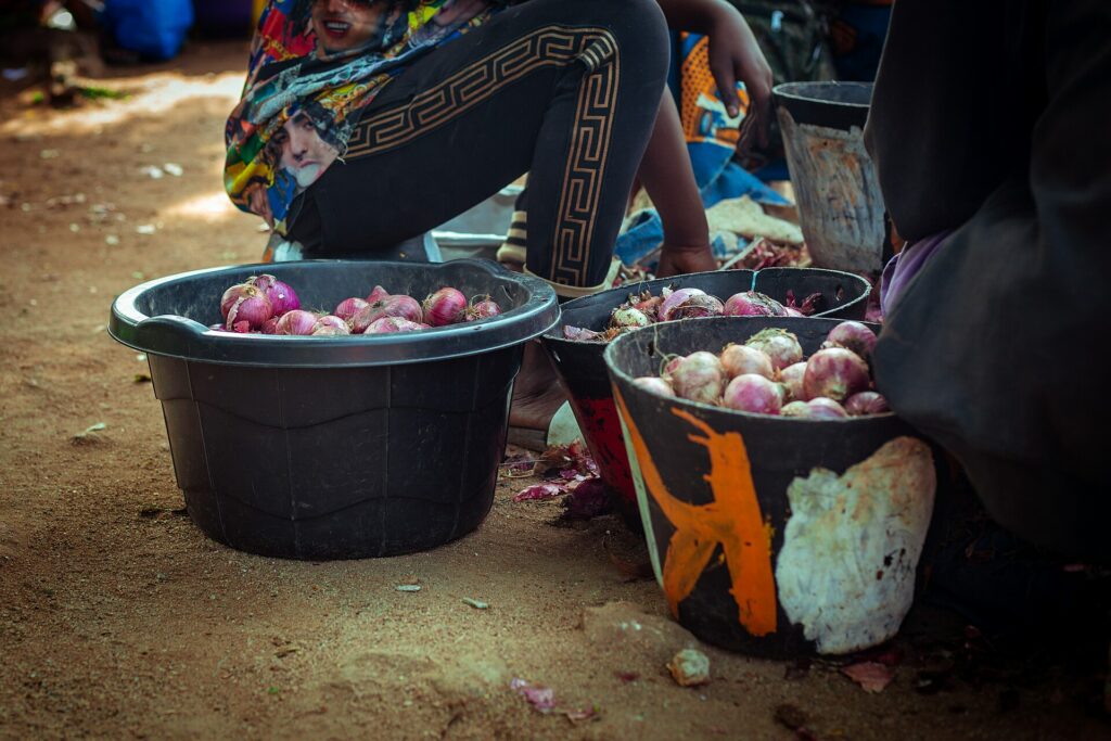 Bassines d'oignons rouges et blancs posées au sol au marché de Bouaké