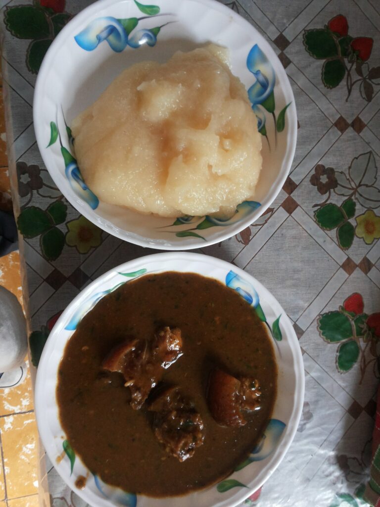 Assiette de placali accompagnée d'une sauce sombre avec morceaux de viande