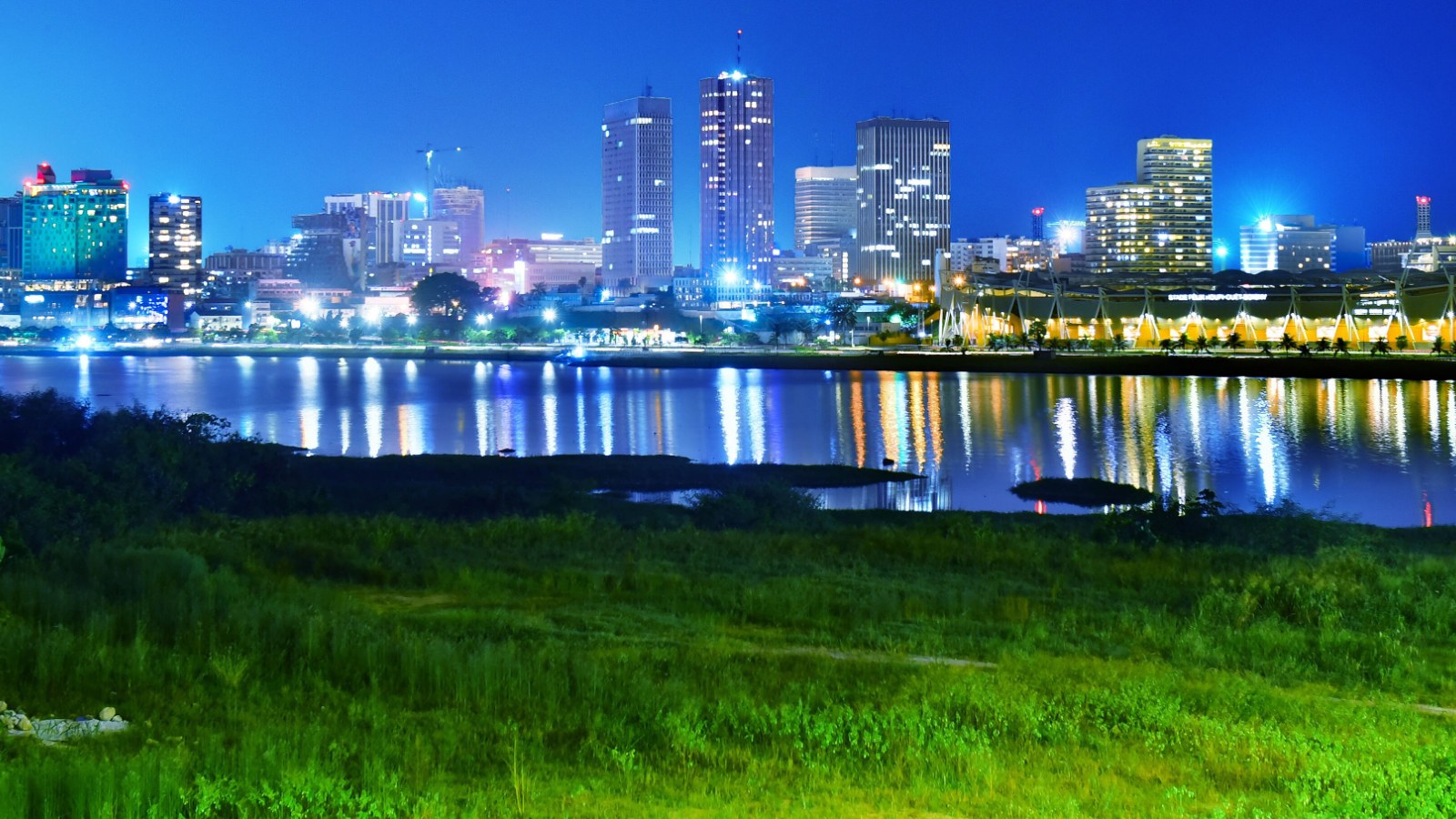 Les tours illuminées du Plateau, à Abidjan, se reflétant de nuit dans la lagune Ébrié