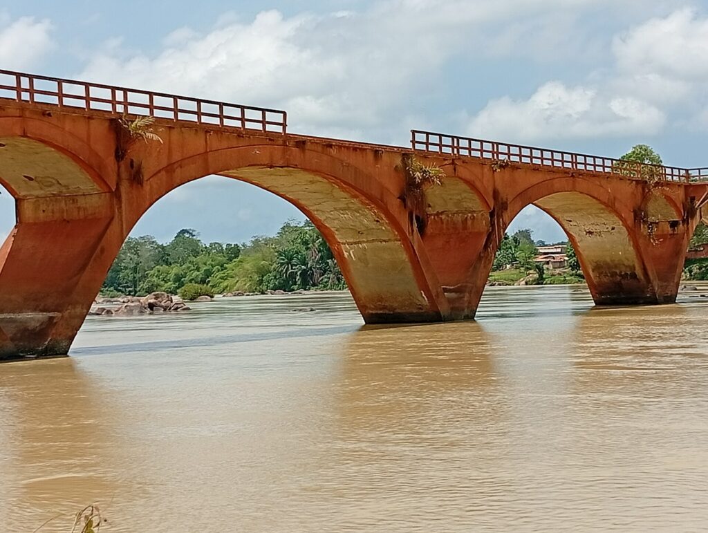 Pont Weygand à arches, en briques rouges, franchissant une rivière à Sassandra