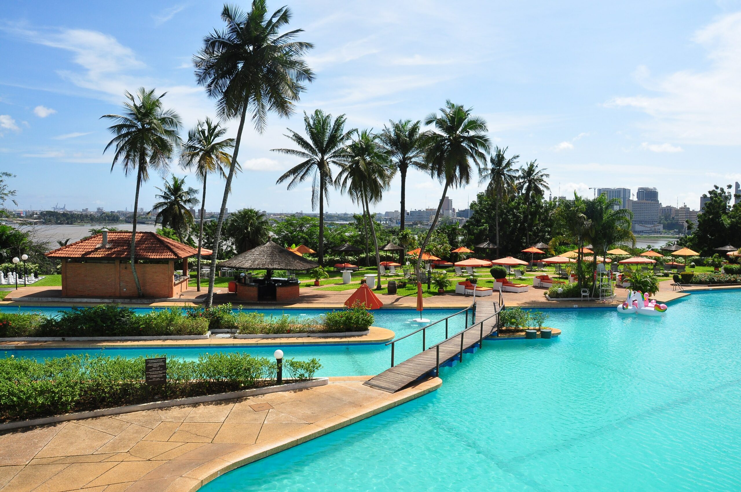 Piscine et jardins tropicaux du Sofitel Abidjan Hôtel Ivoire, à Cocody, avec les tours du Plateau à l'horizon