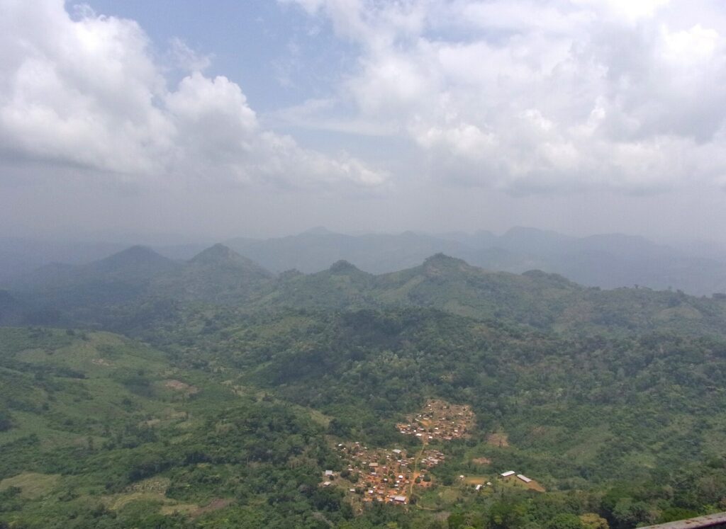 Panorama sur les montagnes boisées et un village depuis le sommet du mont Tonkoui